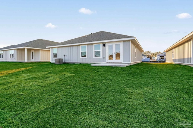 rear view of property featuring a yard, french doors, central AC, and board and batten siding