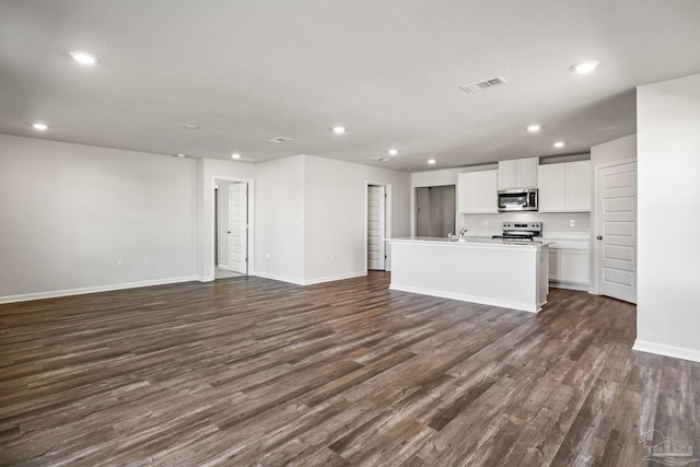 unfurnished living room featuring dark wood-type flooring, visible vents, baseboards, and recessed lighting
