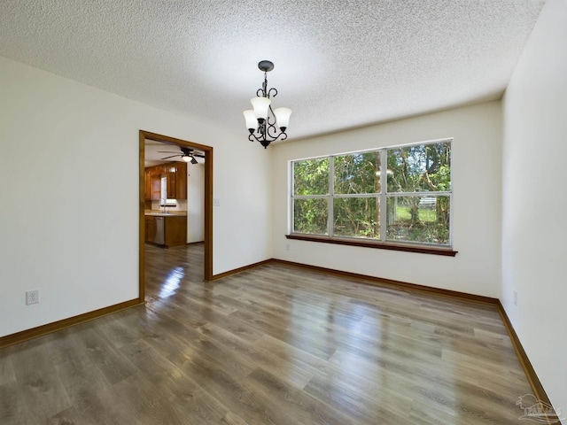 empty room with dark hardwood / wood-style floors, a textured ceiling, and an inviting chandelier