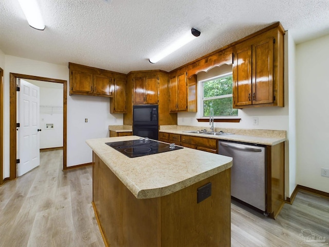 kitchen featuring a kitchen island, sink, light hardwood / wood-style floors, black appliances, and a textured ceiling