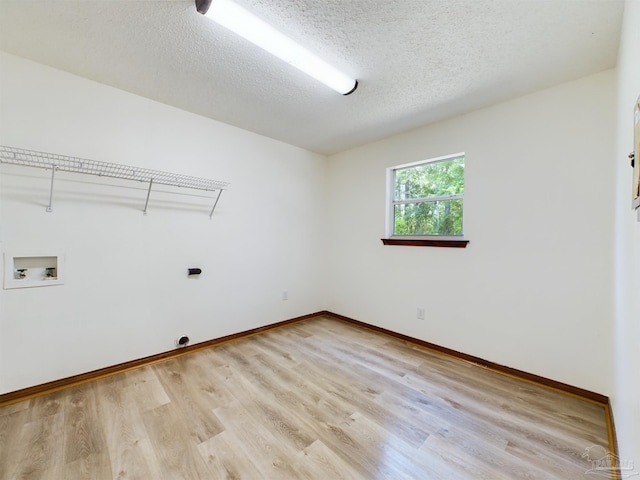 laundry area with hookup for a washing machine, light hardwood / wood-style floors, and a textured ceiling