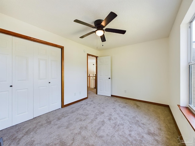 unfurnished bedroom with ceiling fan, light colored carpet, and a closet