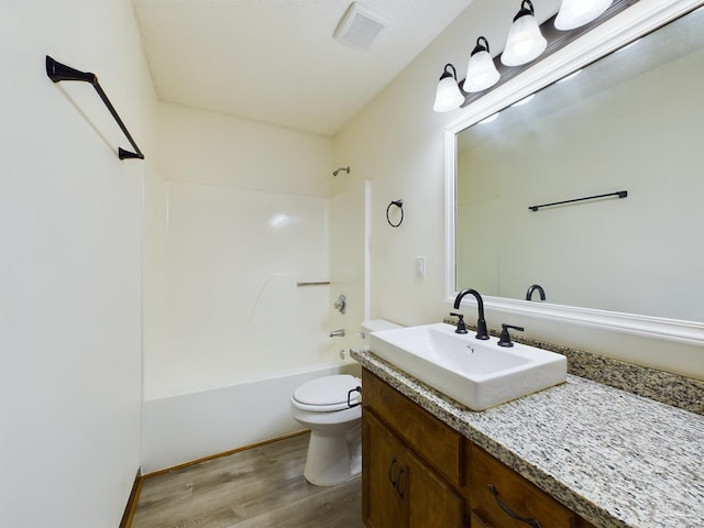 full bathroom with vanity, hardwood / wood-style flooring, shower / tub combination, and toilet