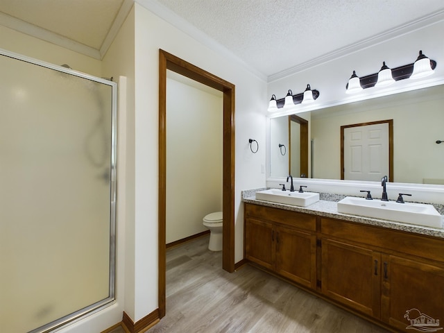 bathroom with ornamental molding, hardwood / wood-style floors, a textured ceiling, and a shower with shower door