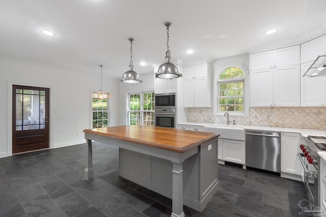 kitchen featuring stainless steel appliances, butcher block countertops, a sink, and tasteful backsplash