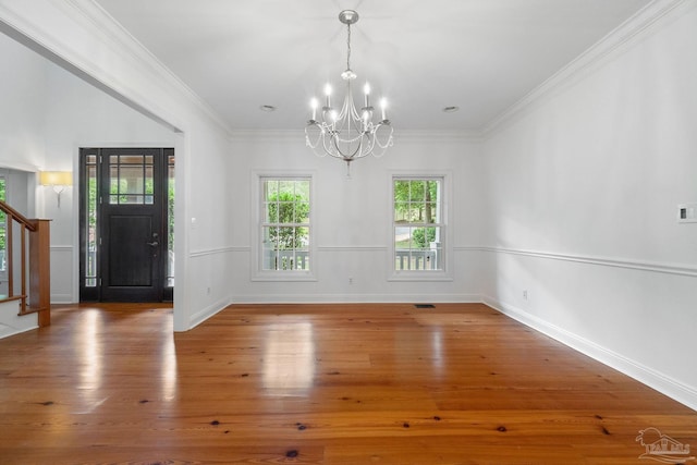 unfurnished dining area featuring wood finished floors, stairway, baseboards, an inviting chandelier, and ornamental molding