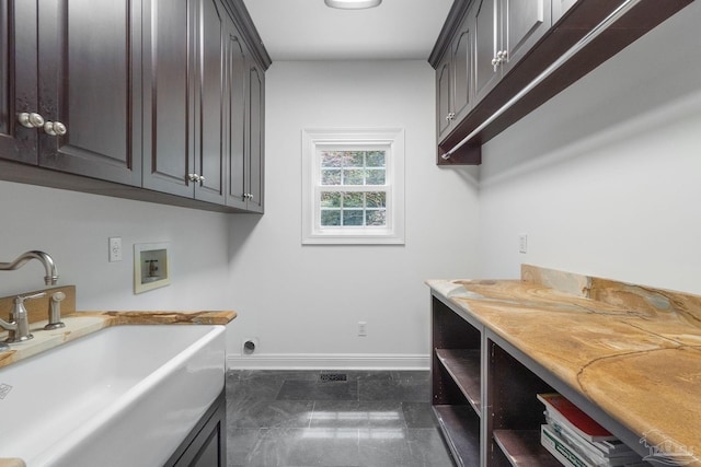 clothes washing area with a sink, baseboards, cabinet space, and hookup for a washing machine