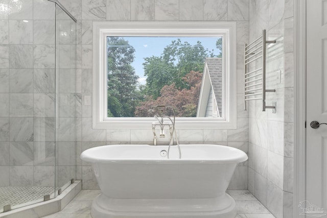 bathroom with marble finish floor, a shower stall, a soaking tub, and tile walls