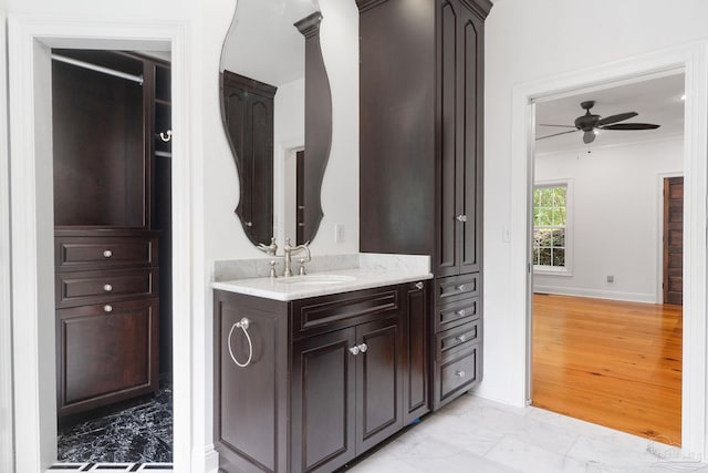 bathroom featuring ceiling fan, vanity, marble finish floor, baseboards, and ornamental molding