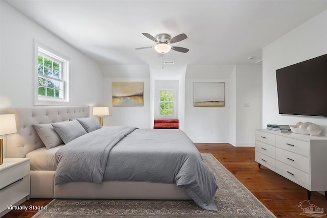 bedroom with multiple windows, a ceiling fan, dark wood-type flooring, and visible vents
