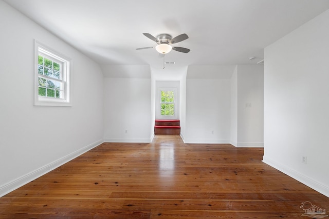 empty room featuring ceiling fan, visible vents, baseboards, and hardwood / wood-style flooring