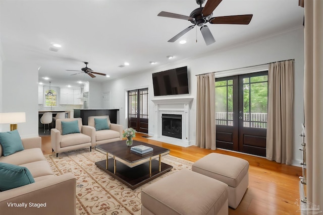 living area with crown molding, light wood-style floors, ceiling fan, recessed lighting, and a fireplace with flush hearth