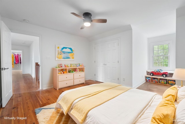 bedroom featuring light wood-style floors, baseboards, a ceiling fan, and a closet