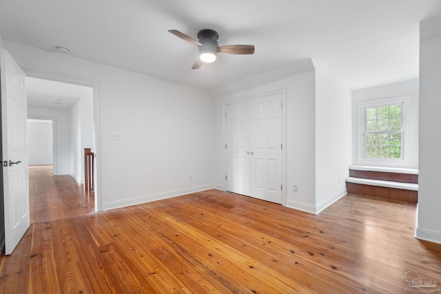 unfurnished bedroom with baseboards, a ceiling fan, a closet, and light wood-type flooring