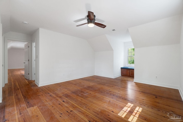 additional living space with a ceiling fan, visible vents, baseboards, lofted ceiling, and hardwood / wood-style floors
