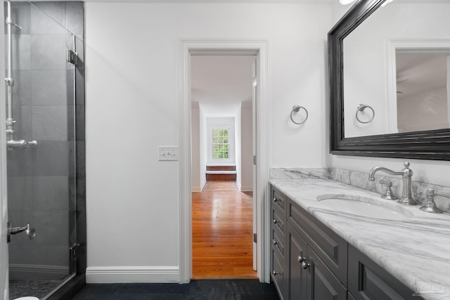 full bath with vanity, baseboards, and a stall shower