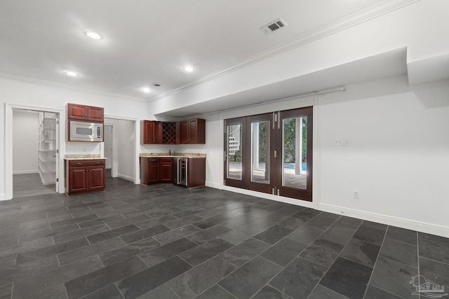 unfurnished living room with crown molding, baseboards, wine cooler, indoor bar, and visible vents