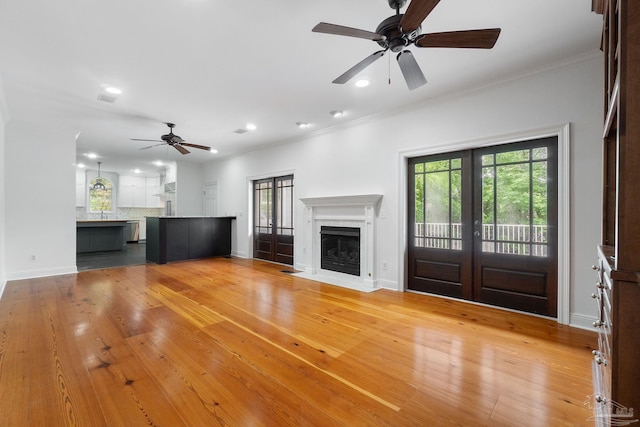 unfurnished living room with a fireplace, french doors, a ceiling fan, recessed lighting, and ornamental molding