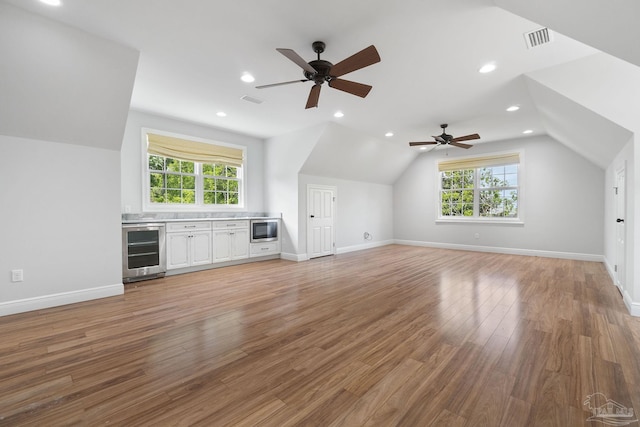 additional living space featuring visible vents, light wood finished floors, a ceiling fan, wine cooler, and vaulted ceiling