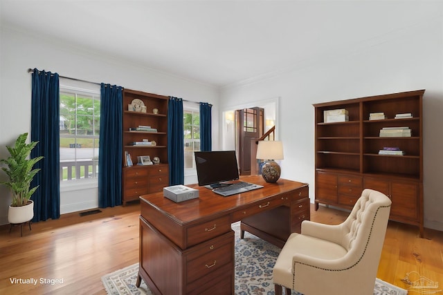 office space featuring a healthy amount of sunlight, crown molding, light wood finished floors, and visible vents