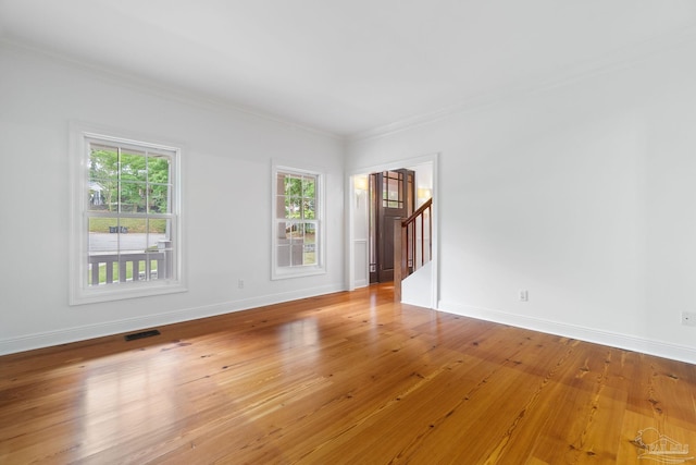 spare room featuring crown molding, plenty of natural light, stairway, and visible vents