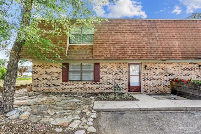 2707 E De Soto St, Pensacola, FL 32503 - view of front of house featuring roof with shingles, brick siding, and mansard roof