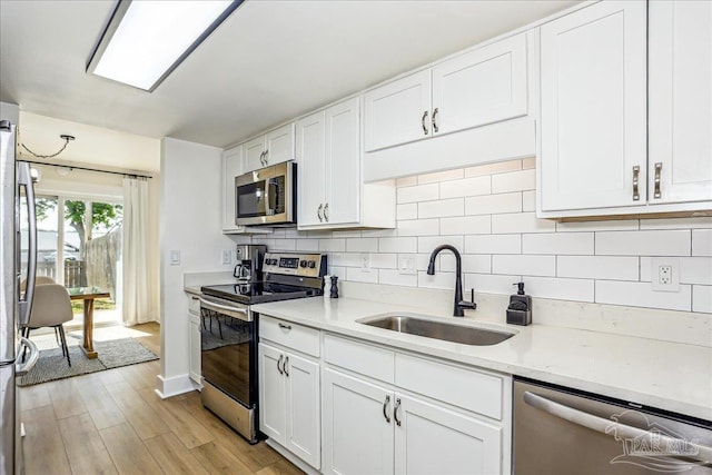 2707 E De Soto St, Pensacola, FL 32503 - kitchen featuring white cabinetry, decorative backsplash, stainless steel appliances, and a sink