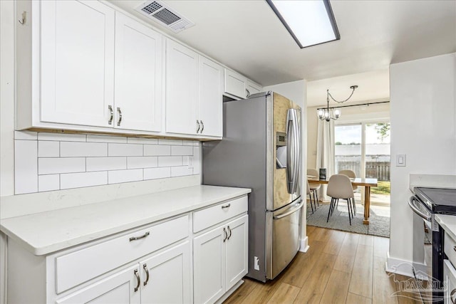 2707 E De Soto St, Pensacola, FL 32503 - kitchen with light wood finished floors, an inviting chandelier, stainless steel fridge, visible vents, and range with electric stovetop