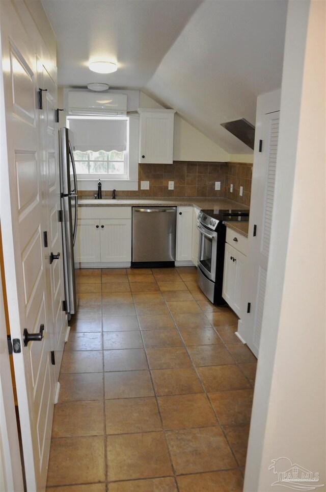 4565 Forsyth St, Bagdad, FL 32583 - kitchen with appliances with stainless steel finishes, tasteful backsplash, white cabinets, vaulted ceiling, and a wall mounted AC