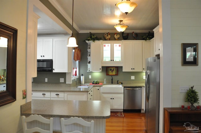 4565 Forsyth St, Bagdad, FL 32583 - kitchen with appliances with stainless steel finishes, a sink, wood finished floors, white cabinetry, and hanging light fixtures