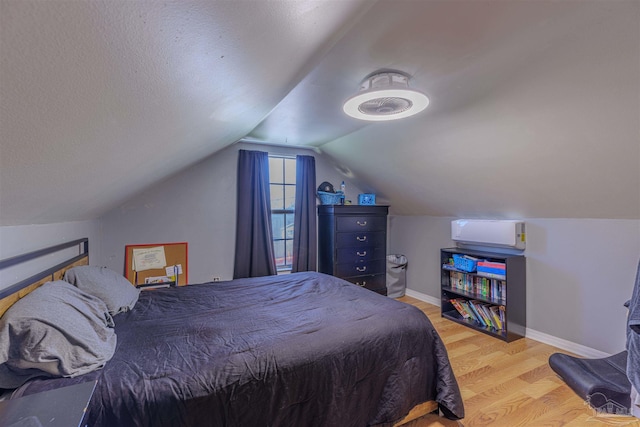 bedroom featuring vaulted ceiling, a textured ceiling, baseboards, and wood finished floors