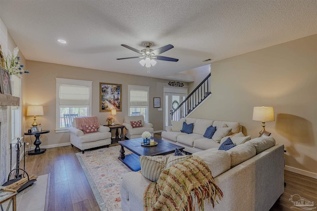 living room featuring visible vents, baseboards, ceiling fan, stairs, and dark wood-style flooring