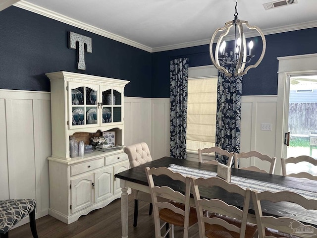 dining area featuring visible vents, a wainscoted wall, ornamental molding, an inviting chandelier, and dark wood-style flooring