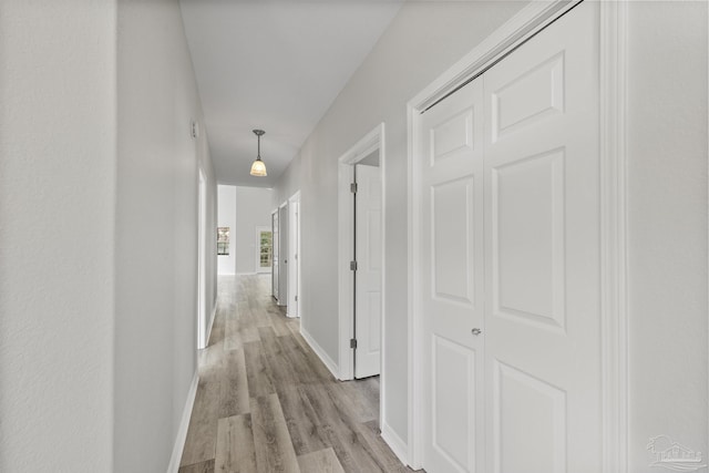 corridor with light wood finished floors and baseboards