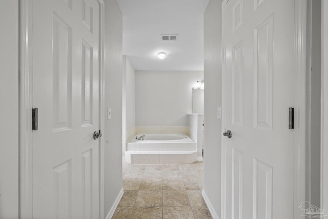 bathroom with a garden tub, baseboards, and visible vents