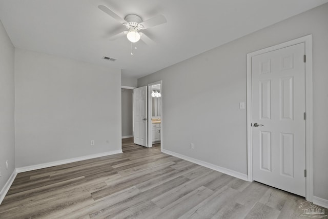 unfurnished bedroom with light wood-type flooring, visible vents, baseboards, and ensuite bathroom