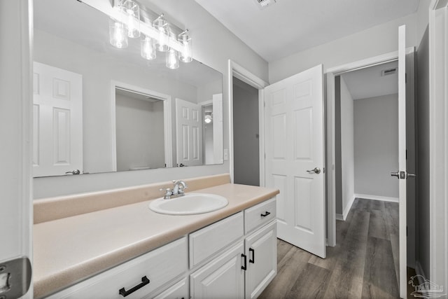 bathroom with visible vents, wood finished floors, vanity, and baseboards