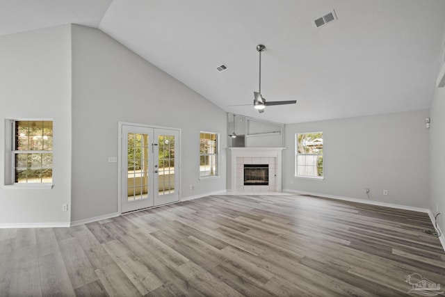 unfurnished living room featuring a tile fireplace, visible vents, wood finished floors, and french doors