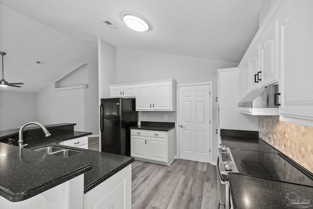 kitchen featuring visible vents, white cabinets, freestanding refrigerator, under cabinet range hood, and a sink