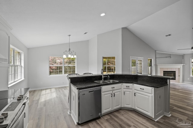 kitchen featuring white cabinets, open floor plan, stainless steel appliances, a fireplace, and a sink