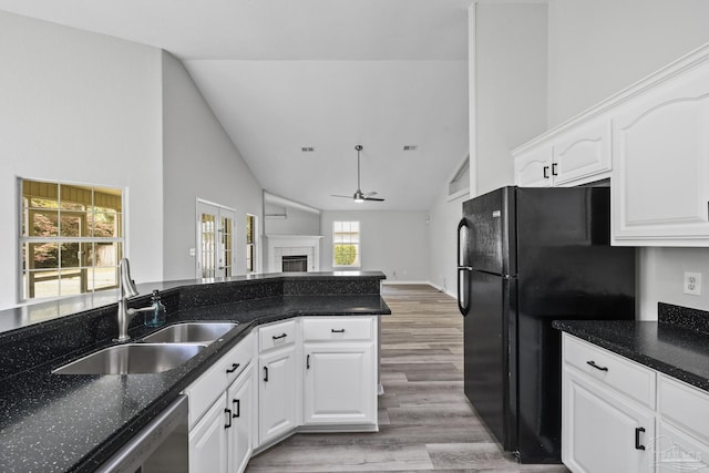 kitchen featuring a tile fireplace, a sink, a ceiling fan, white cabinets, and freestanding refrigerator