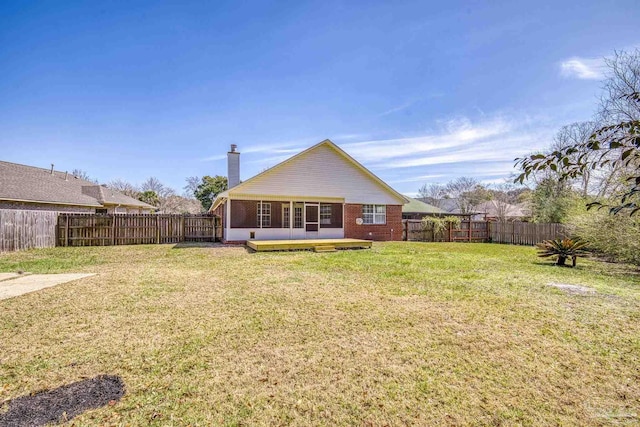 back of house featuring a fenced backyard, a lawn, a chimney, and brick siding