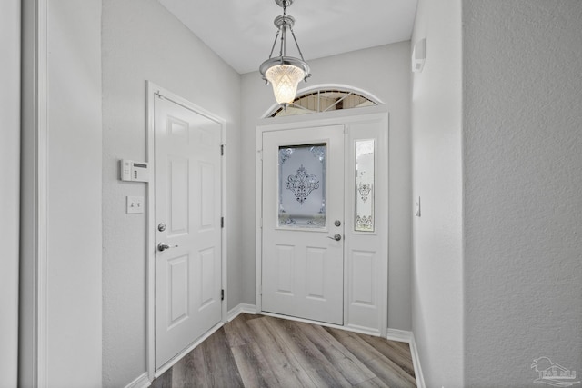 entrance foyer featuring a notable chandelier, wood finished floors, and baseboards