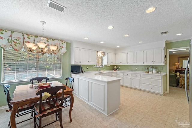 kitchen featuring white cabinetry, sink, an inviting chandelier, kitchen peninsula, and pendant lighting