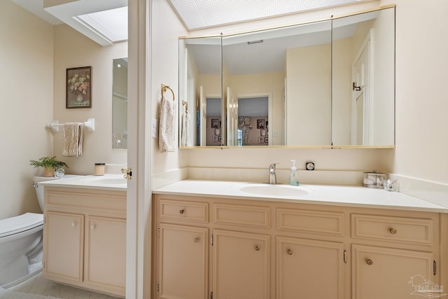 bathroom featuring a skylight, vanity, and toilet