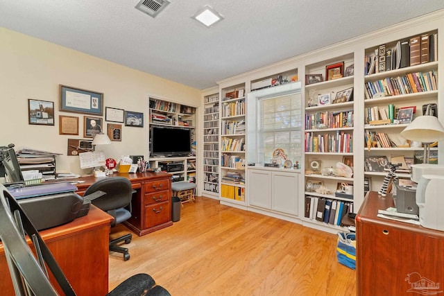 home office with a textured ceiling and light hardwood / wood-style floors