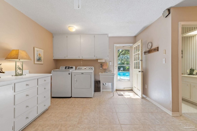 laundry room featuring cabinets, a textured ceiling, sink, independent washer and dryer, and light tile patterned flooring