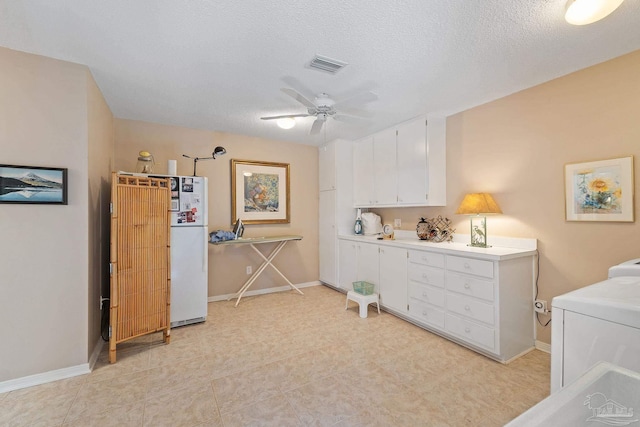 washroom with cabinets, a textured ceiling, washer / clothes dryer, and ceiling fan