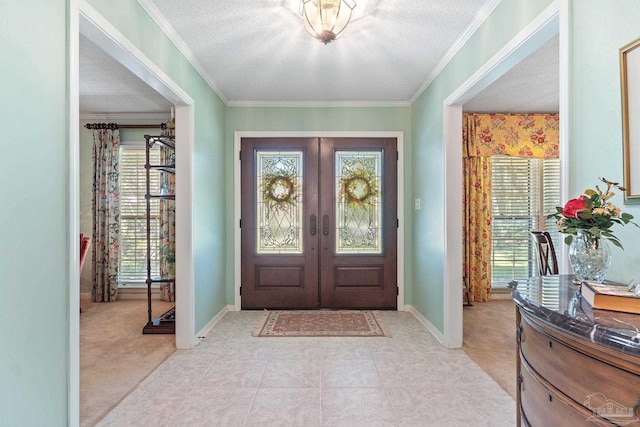 foyer entrance featuring light carpet, french doors, a textured ceiling, and ornamental molding