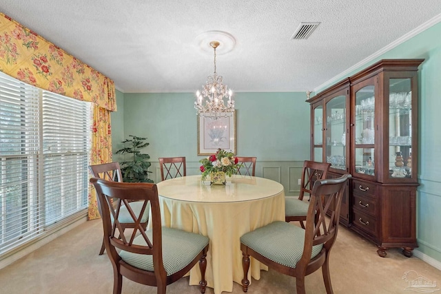 dining space featuring ornamental molding, a textured ceiling, light carpet, and a chandelier